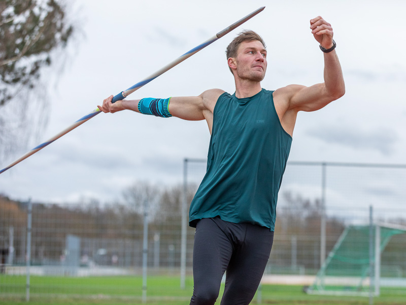 Thomas Röhler hält einen Speer in der Hand und ist kurz davor ihn zu werfen. Er trägt dabei eine Ellbogen-Bandage und ist auf dem Trainingsplatz.