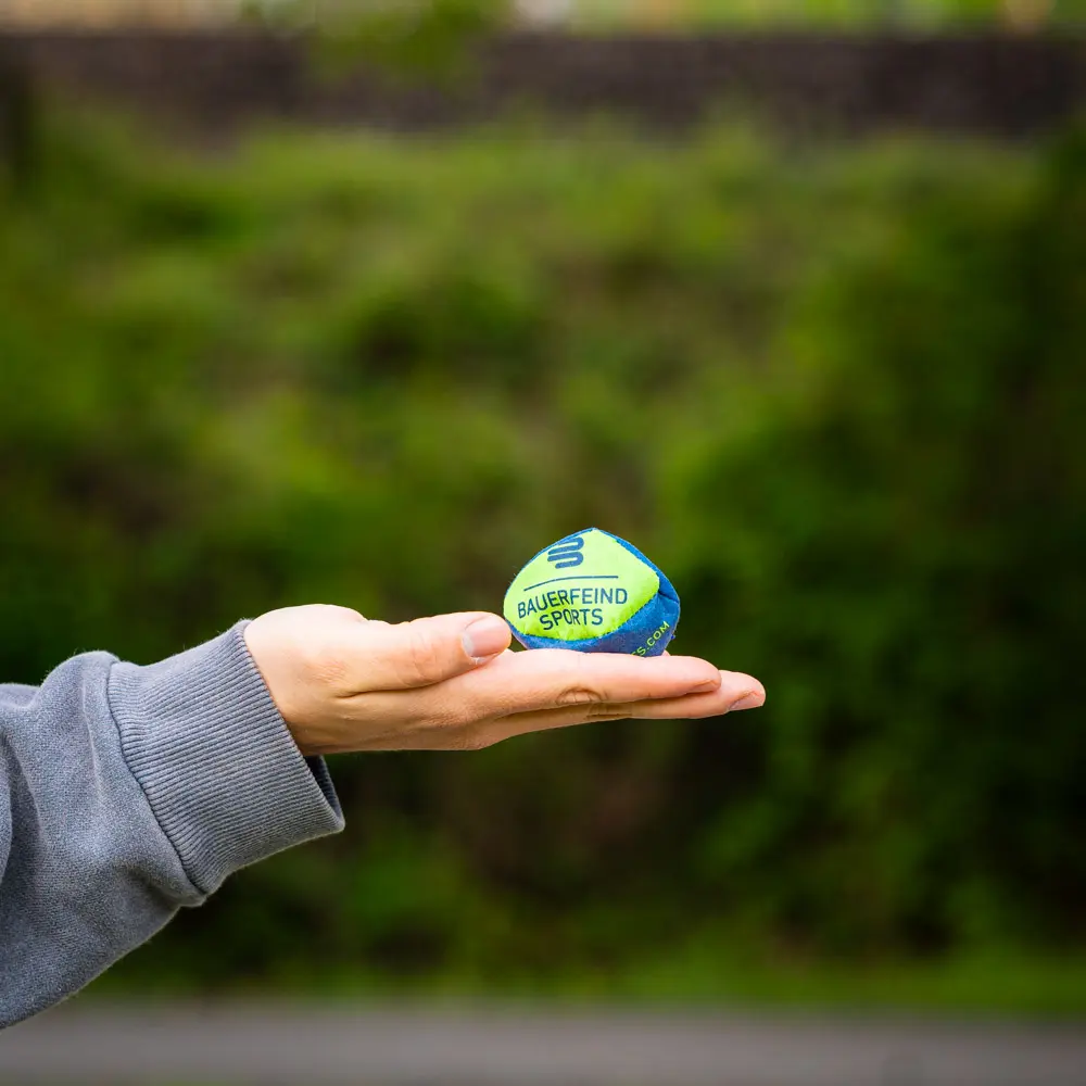 Hand houdt een kleine Bauerfeind Sports bal vast, ideaal voor training en coördinatie.