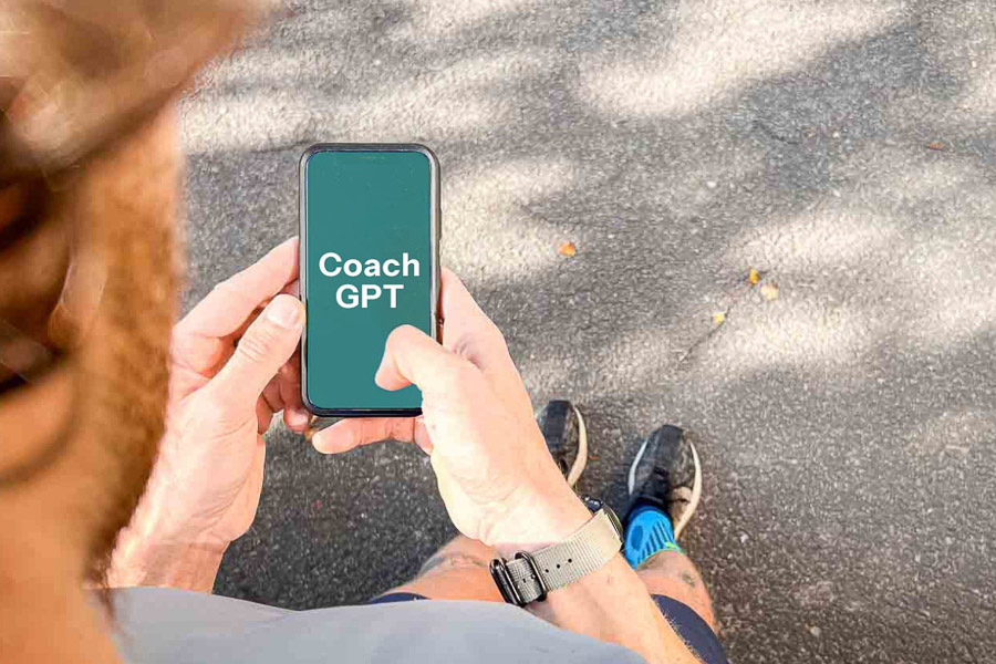 Een loper houdt een smartphone vast met daarop "Coach GPT" weergegeven. De scène toont het gebruik van AI-technologie ter ondersteuning van hardlooptraining.