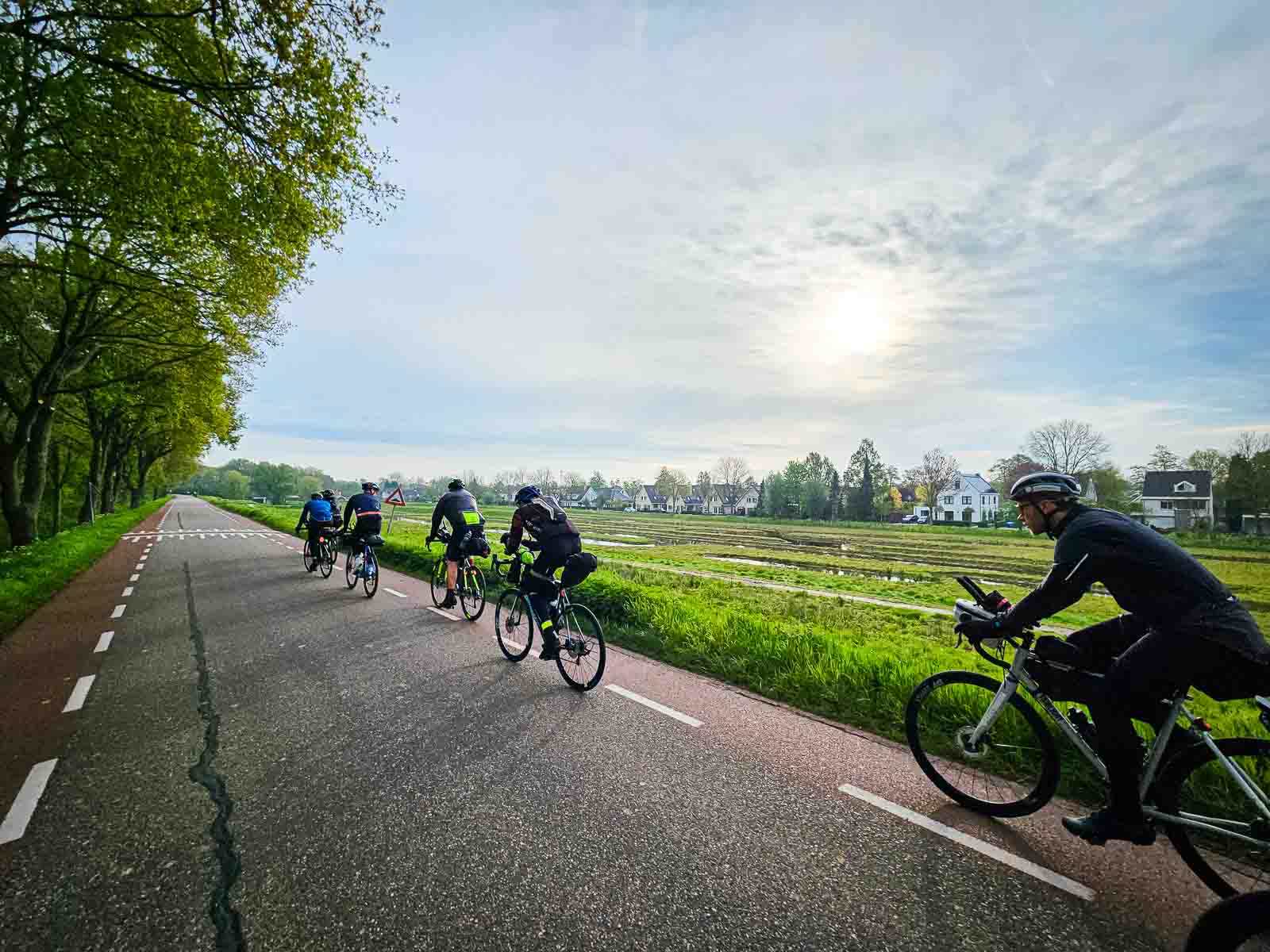 Verschillende fietsers rijden achter elkaar op een weg in de Race om Nederland