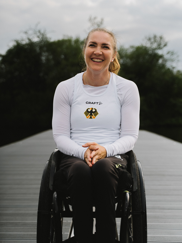 De Duitse atlete Edina Müller zit in een rolstoel op een steiger en lacht naar de camera.