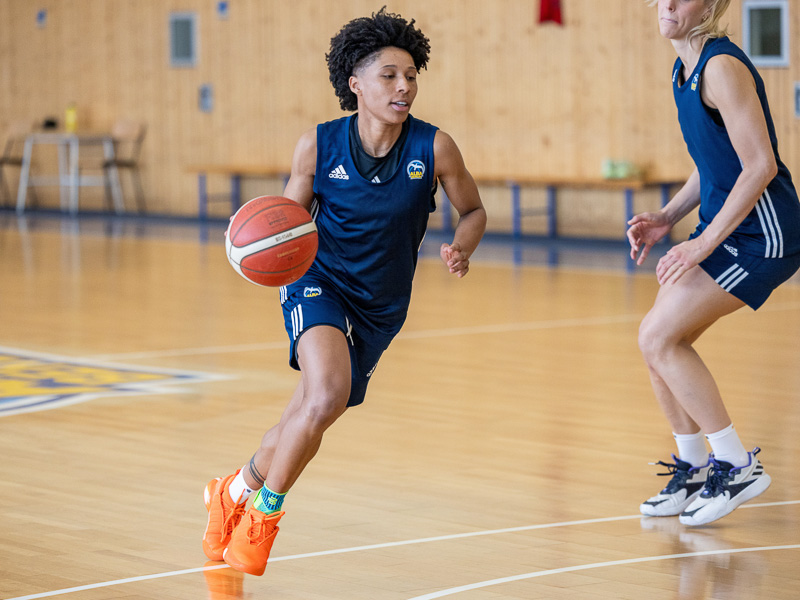 Een basketbalspeelster van Alba Berlin dribbelt en gaat langs een andere speelster."