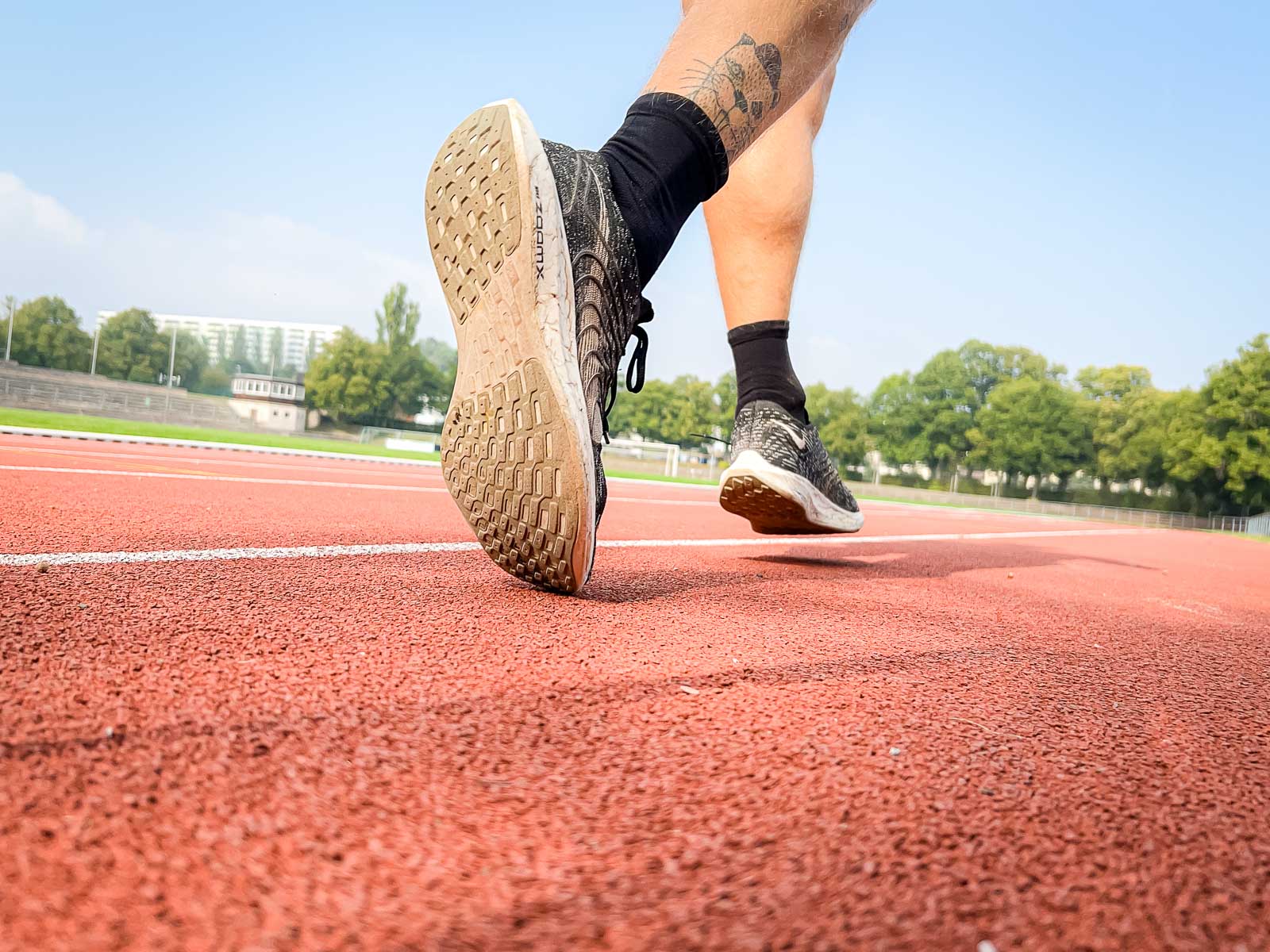 Close-up van de schoenen van een loper op de rode renbaan, klaar voor training. De scène symboliseert vastberadenheid en sportieve doelen.