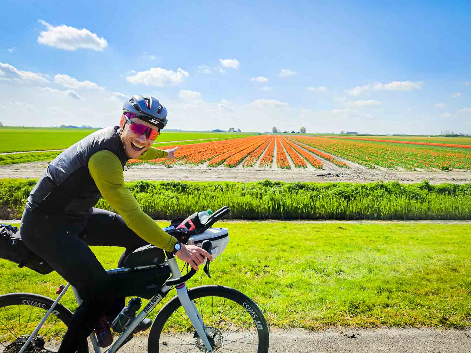 Een deelnemer aan de Race om Nederland geniet van de kleurrijke bloemen en wijst ernaar