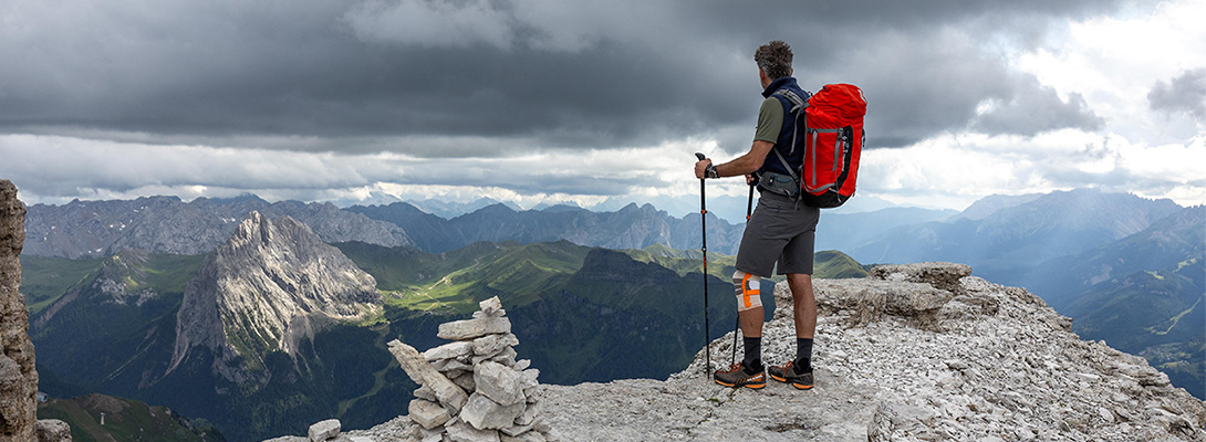 Bergbeklimmer op een bergtop die een outdoor kniebandage draagt