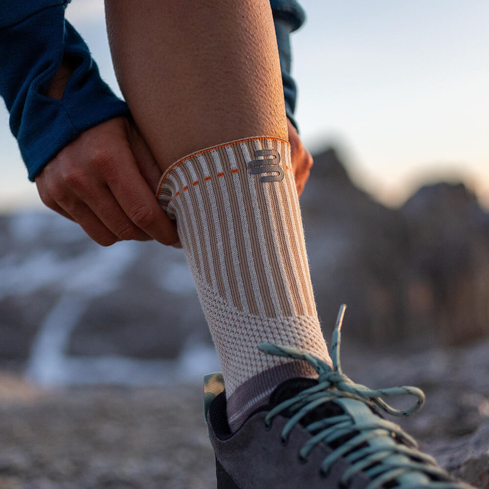 Persoon trekt ademende, antislip outdoor sok aan, ideaal voor wandelen en bergbeklimmen.