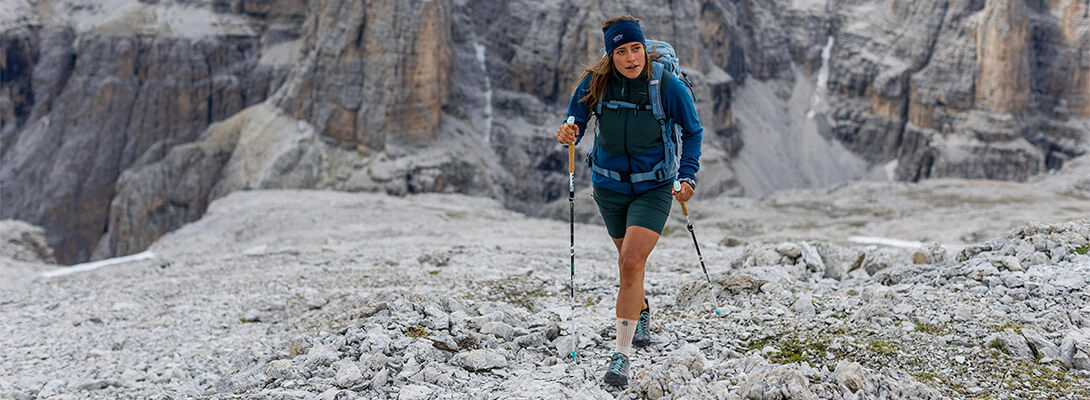 Vrouw aan het wandelen op rotsachtig terrein in de Alpen.