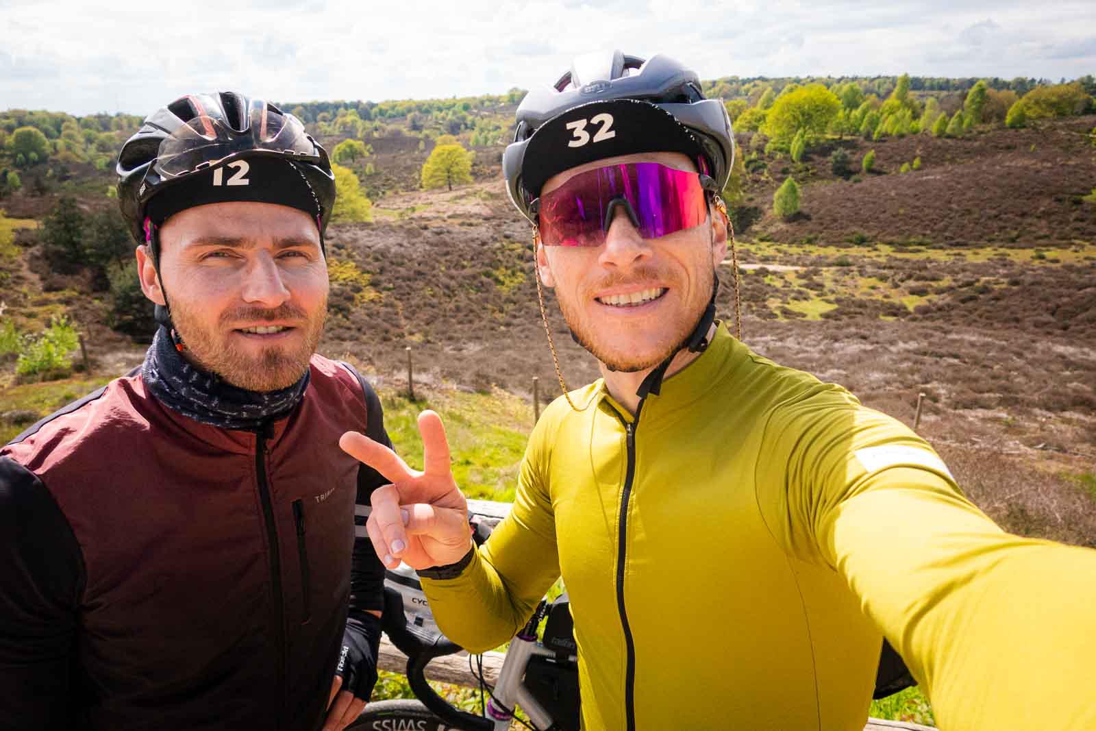 Twee fietsers staan voor een prachtig heidelandschap en nemen een selfie