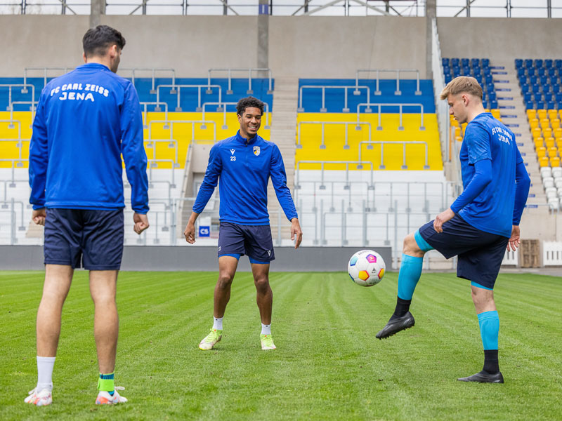 Drie spelers van FC Carl Zeiss Jena in het stadion tijdens de training met een voetbal, die verschillende Bauerfeind Sports producten dragen